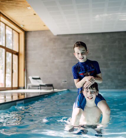Younger brother sitting on older brother's shoulders in swimming pool at Bear Lodge