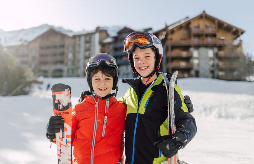 Two smiling boys in ski gear outside Bear Lodge in Arc 1950