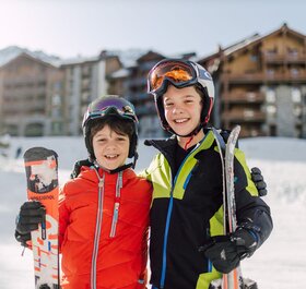 Two smiling boys standing with skis outside Bear Lodge in Arc 1950