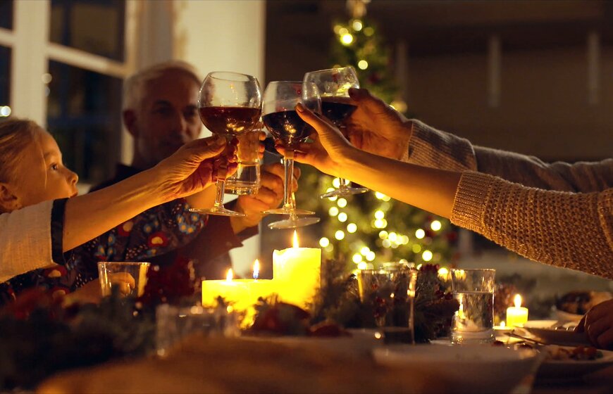 Family group raising glasses at evening Christmas meal