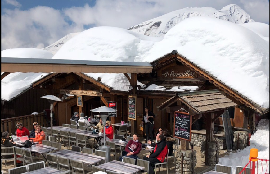 Terrace outside mountain restaurant with lots of snow on roof 