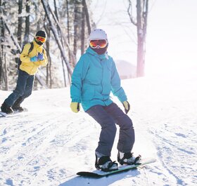 Two snowboarders in sunshine on snowy slope