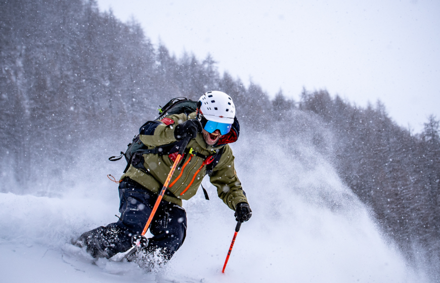 Smiling TDC ski instructor skiing down powder slope in Val d'Isere