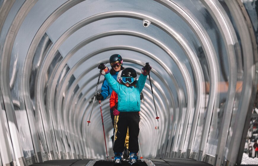 Smiling mother and child on magic carpet ski lift