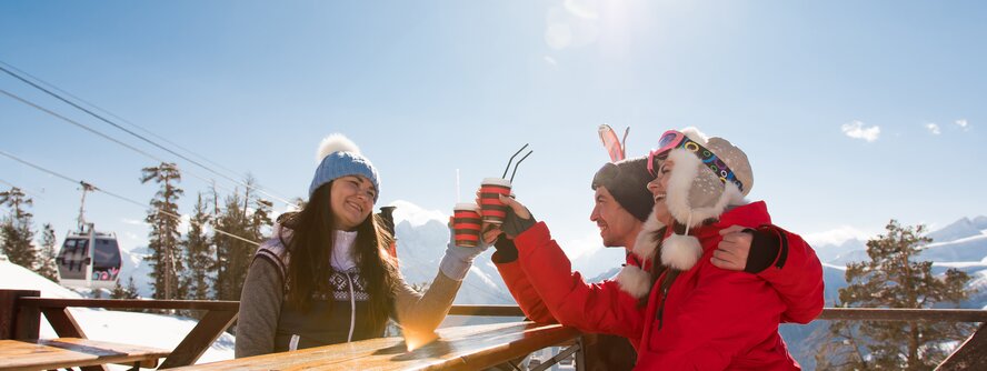 Friends enjoying apres ski on a sunny restaurant terrace