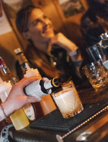 Hand pouring bitters into a cocktail glass
