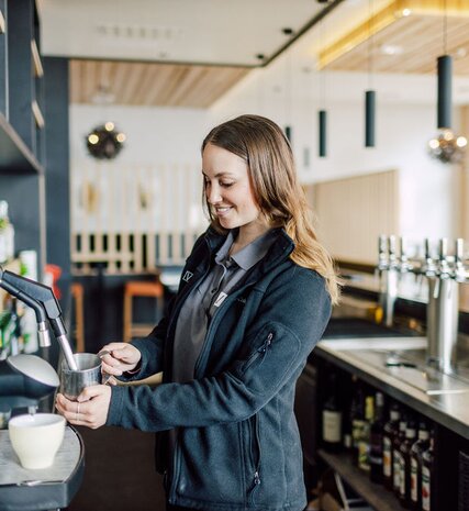 Smiling VIP SKI staff member heating milk in Bear Lodge bar