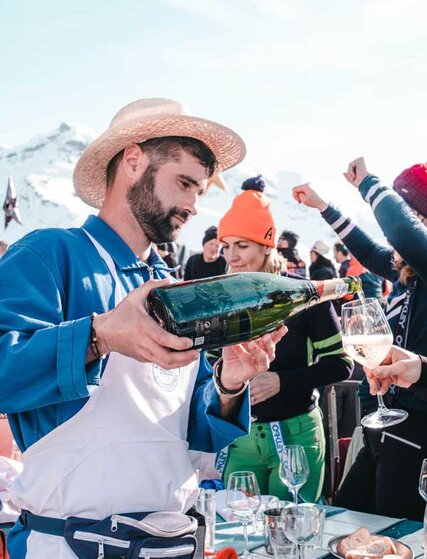 Waiter wearing sunhat pouring wine into glass on sunny terrace