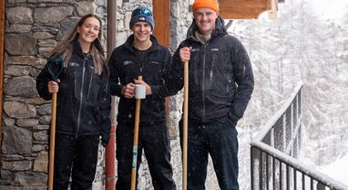 three members of VIP SKI staff stood outside a chalet with snow shovels