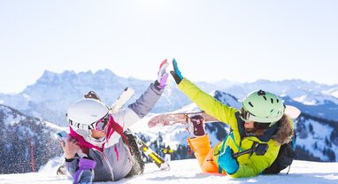 two female friends in the snow with ski and snowboarding equipment