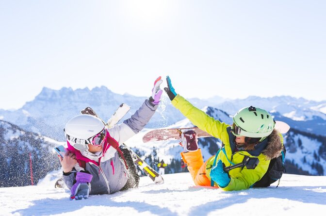two female friends in the snow with ski and snowboarding equipment