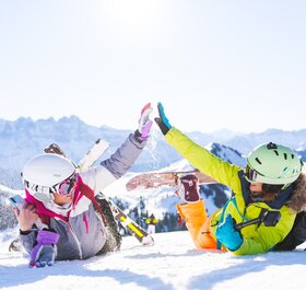two female friends in the snow with ski and snowboarding equipment