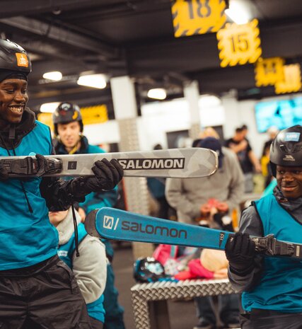 Smiling young boys holding skis in rental shop at indoor snow centre