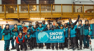 Group of Snow Camp young people holding Snow Camp banner at indoor snow centre