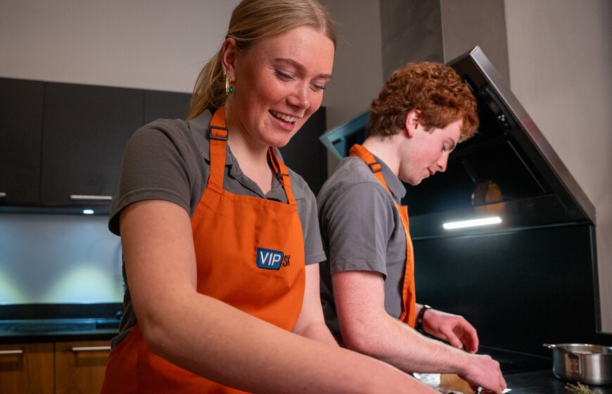 Smiling male and female VIP SKI chalet hosts preparing dinner in catered chalet