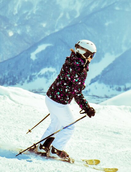 Female skier skiing down slope