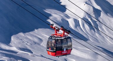 Red cable car in La Plagne with snowy mountains in background