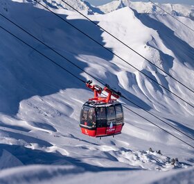 Red cable car in La Plagne with snowy mountains in background