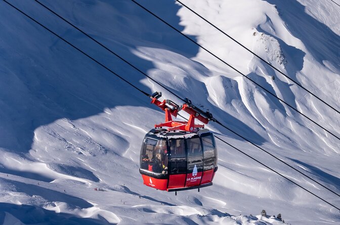 Red cable car in La Plagne with snowy mountains in background