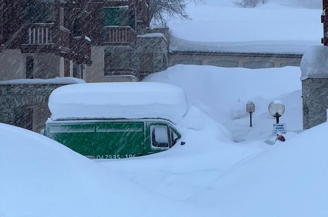 Green van covered in deep snow in Val d'Isere snowstorm