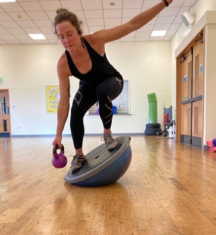 Physio Jo Pollard balancing on balance board holding kettle bell