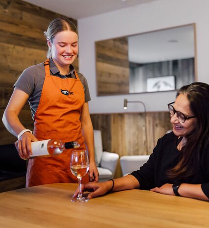 Smiling chalet host pouring wine for a guest