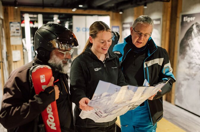 VIP SKI chalet host showing piste map to two male guests