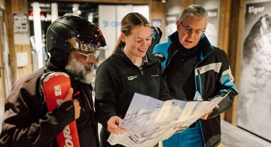 VIP SKI chalet host showing piste map to two male guests