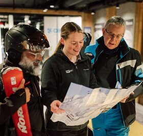 VIP SKI chalet host showing piste map to two male guests
