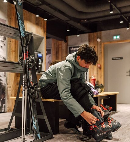 Teenage boy putting ski boots on in luxurious Graciosa ski room