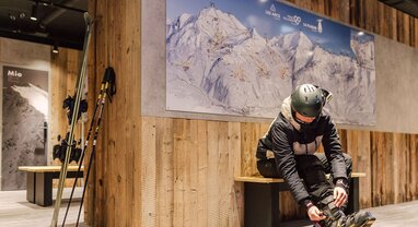 Male skier doing up ski boots in the VIP SKI Graciosa ski room in La Plagne