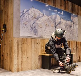 Male skier doing up ski boots in the VIP SKI Graciosa ski room in La Plagne