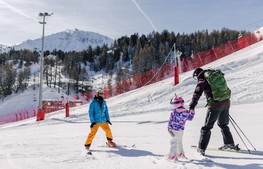 Father and daughter on nursery ski slope with Oxygene instructor