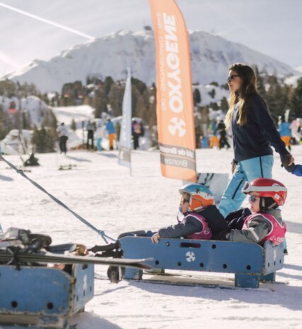 Oxygene ski instructor taking children to ski school on sled