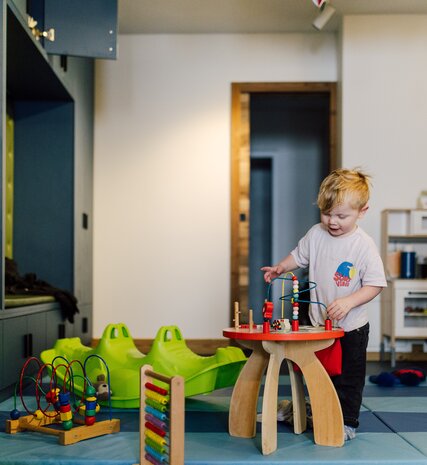 Smiling toddler playing in Bear Cubs playroom