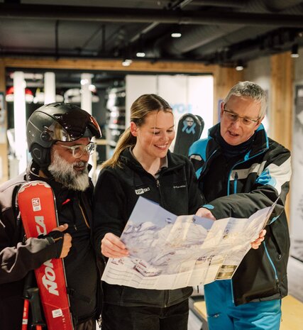 Smiling VIP SKI host looking at piste map with guests in Graciosa boot room