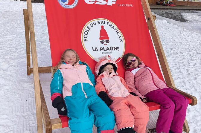 Three smiling children sitting in oversized deckchair in La Plagne