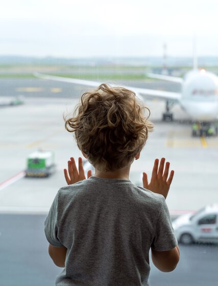 Young boy looking at plane through airport window