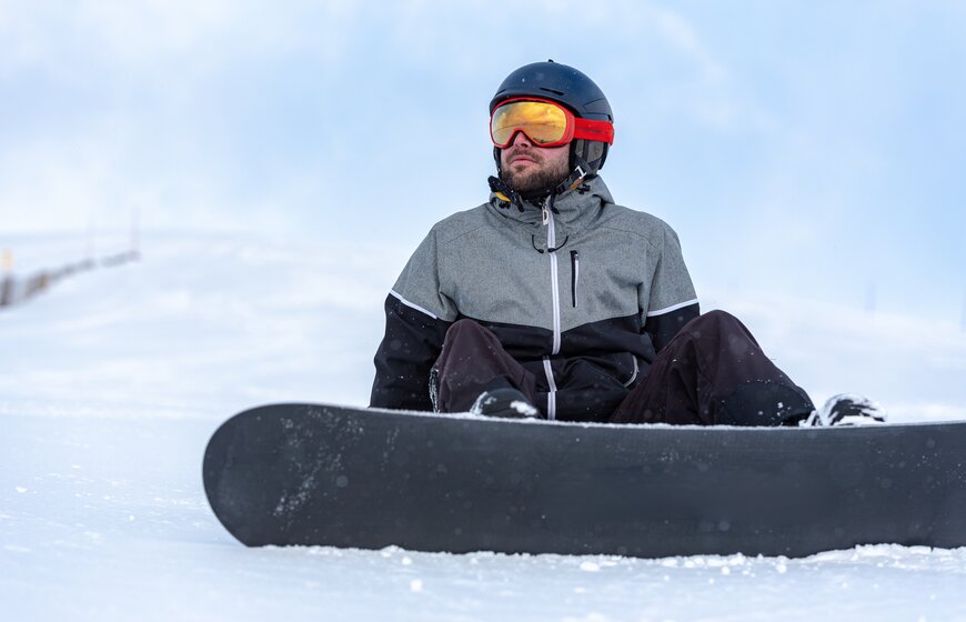 Male snowboarder sitting down on snow