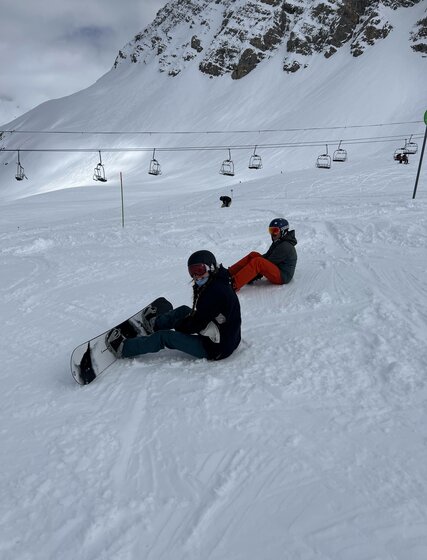 Two snowboarders sitting on snowy piste in Val d'Isere