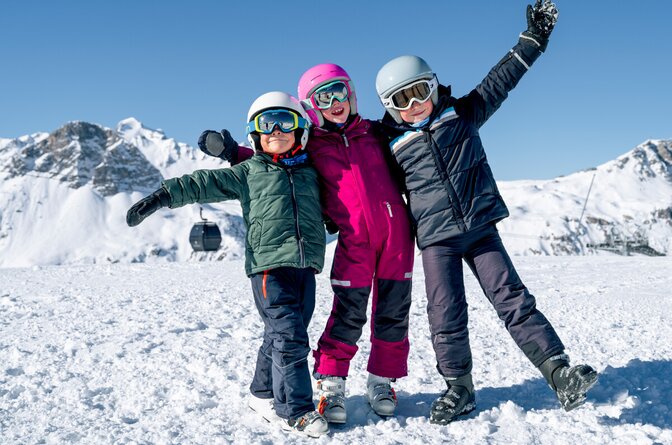 3 smiling children in ski gear on mountain in Val d'Isere