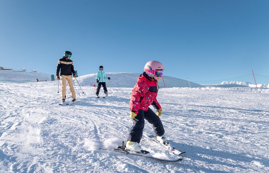 Father and two children skiing on beginner slope in Val d'Isere