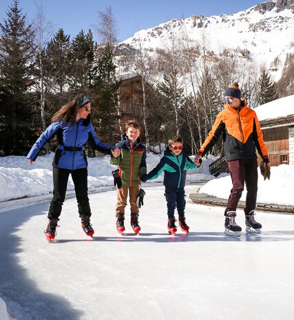 Family of four ice skating on open air rink in Val d'Isère