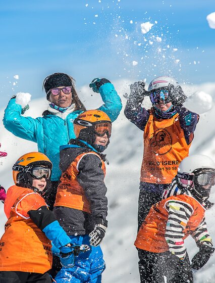 Children having snowball fight with ski instructor