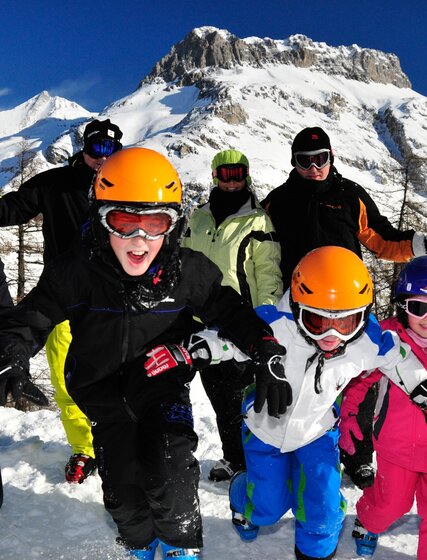 Family group in ski gear smiling and running towards camera