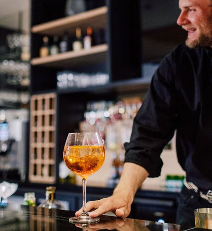 Smiling bar man serving Aperol Spritz
