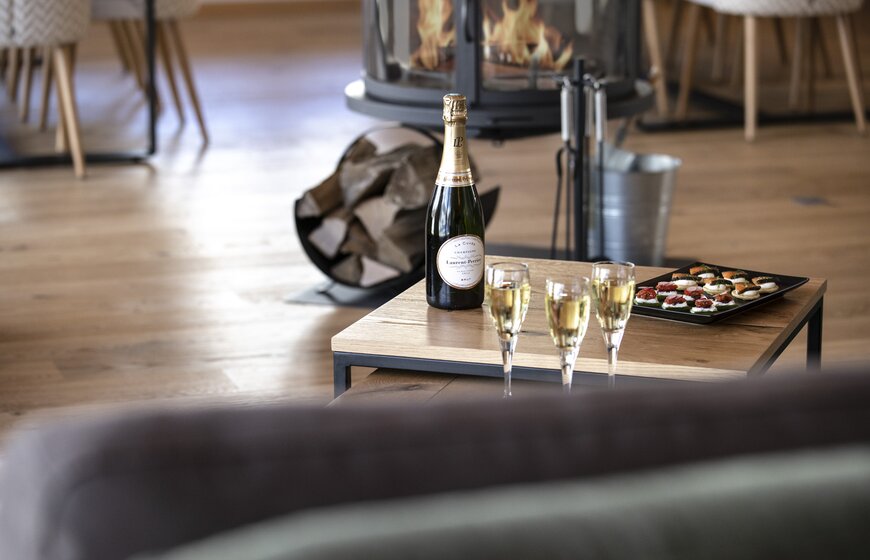 Champagne and canapes on a table, fire lit behind, in No 8 CLUB Bellevarde, Val d'Isere
