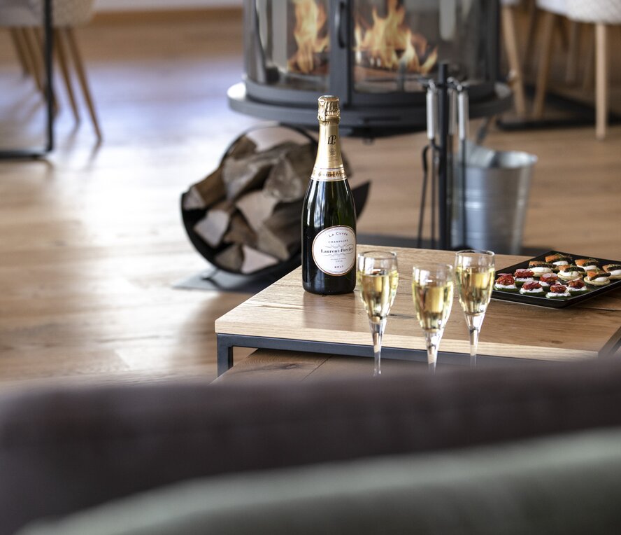Champagne and canapes on a table, fire lit behind, in No 8 CLUB Bellevarde, Val d'Isere