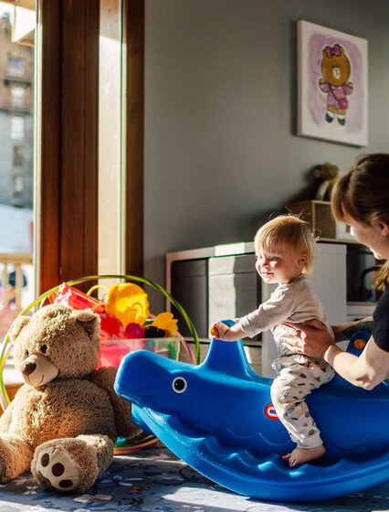 Smiling toddler playing with VIP SKI nanny in Bear Cubs playroom