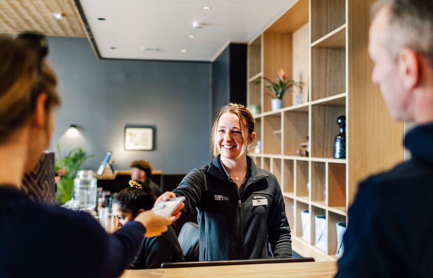Smiling VIP SKI reception staff handing over room key at Bear Lodge ski hotel in Les Arcs